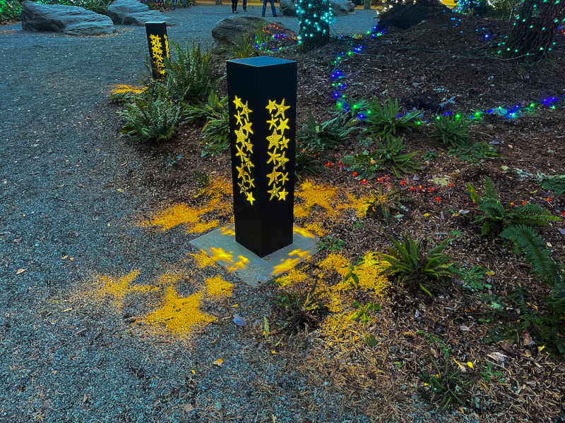 Lit Bollards With Starfish Cutouts At Dusk By Multicolored Lights