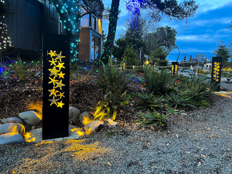 Lit Bollards With Starfish Cutouts At Dusk By Multicolored Lights